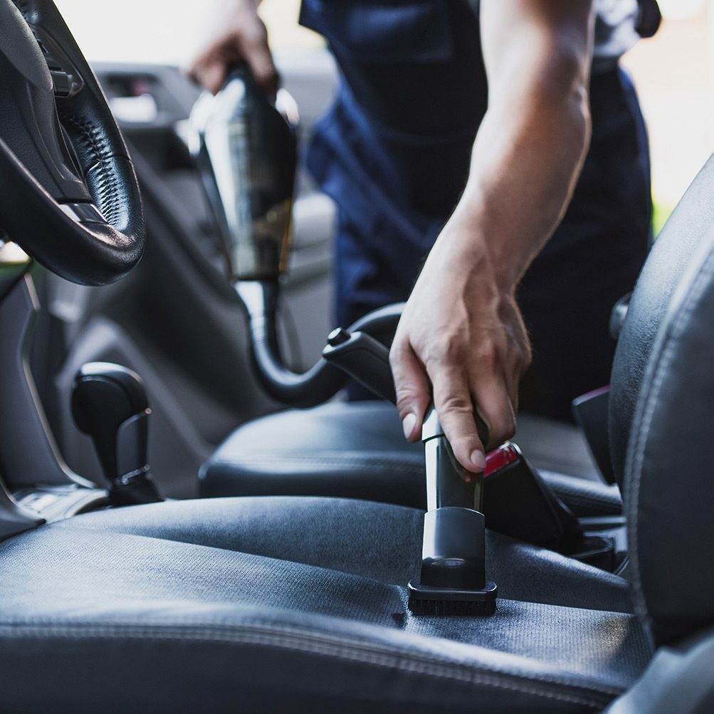 Close up of man vacuuming car seat