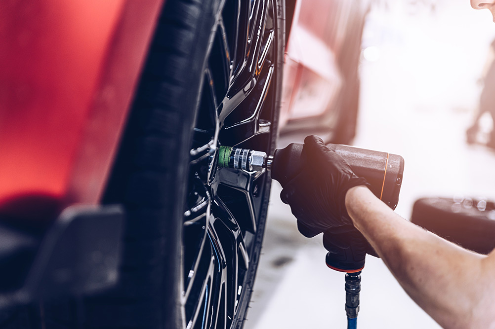 Close up of mechanic fitting tyre onto car